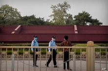 Oficiales de policía chinos usando mascarillas para impedir la propagación del coronavirus hablan con una persona cerca de la Plaza de Tiananmen en Beijing, el 29 de abril de 2020.