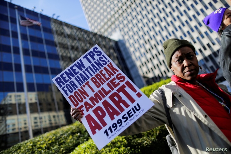 FILE PHOTO: A woman holds a placard as Haitian immigrants and supporters rally to reject DHS Decision to terminate TPS for Haitians, at the Manhattan borough in New York