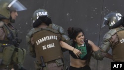 Policías antidisturbios detienen a un estudiante que participaba en las protestas en Santiago.