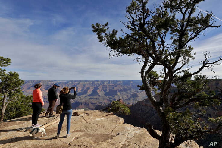 Tanya Wyler takes a photograph as Matthias Zather and Ines Zather, all of Switzerland, gather at the Grand Canyon Friday, May…