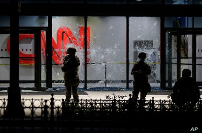Members of the Georgia National Guard stand in front of shattered glass at the CNN Center in the aftermath of a demonstration…