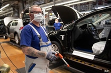 An employee stands near vehicles in production with a face mask in the VW plant in Wolfsburg, Germany, Monday, April 27, 2020…