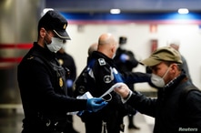 Un policía español reparte tapabocas en una estación del metro de Madrid. El lunes, el gobierno permitió que los trabajarores de construcción y fábricas, regresaran a sus empleos.