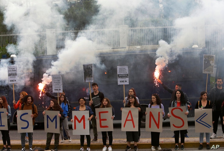 Members of the Greek Communist Party (KKE) youth organisation, hold up flares and placards as they stand outside the U.S…