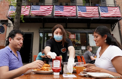 FILE PHOTO: As Phase One of reopening begins in Northern Virginia, a waitress with a face mask to protect against the…