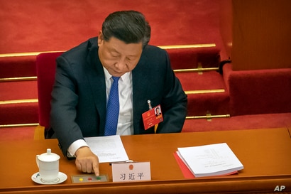 Chinese President Xi Jinping reaches to vote on a piece of national security legislation concerning Hong Kong during the…