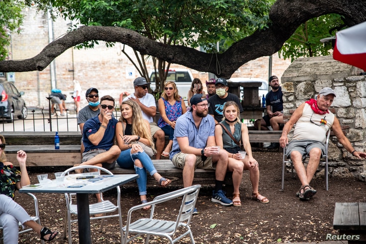 People sit at an outdoor bar and eating area amid the global outbreak of the coronavirus disease (COVID-19), in Austin, Texas,…