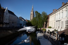 Two pigeons fly across a canal in Bruges, Belgium, during a partial lifting of a lockdown to prevent the spread of coronavirus,…